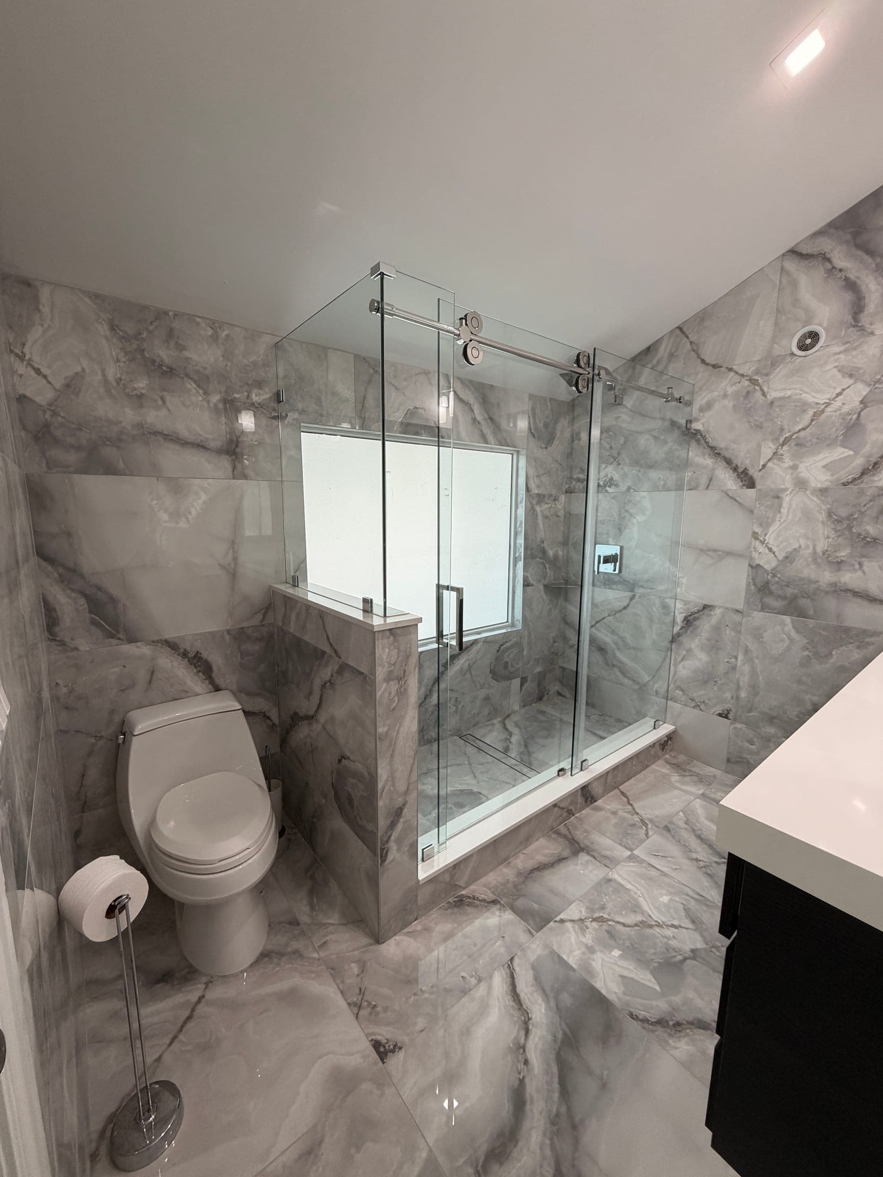 Bathroom vanity with dark cabinetry, white countertop, and framed mirror