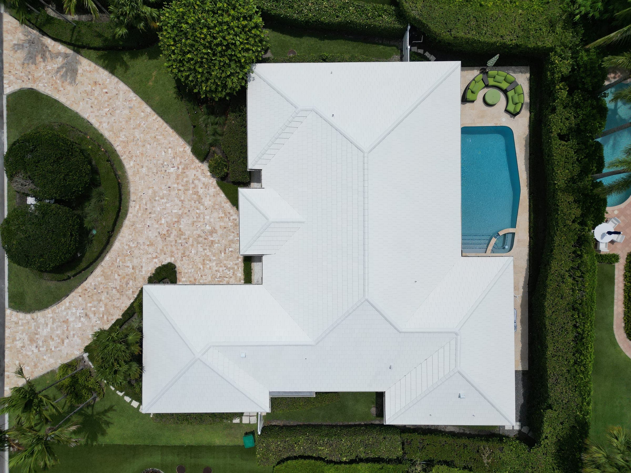 Aerial view of the property showing the roofline, pool, and a paved pathway