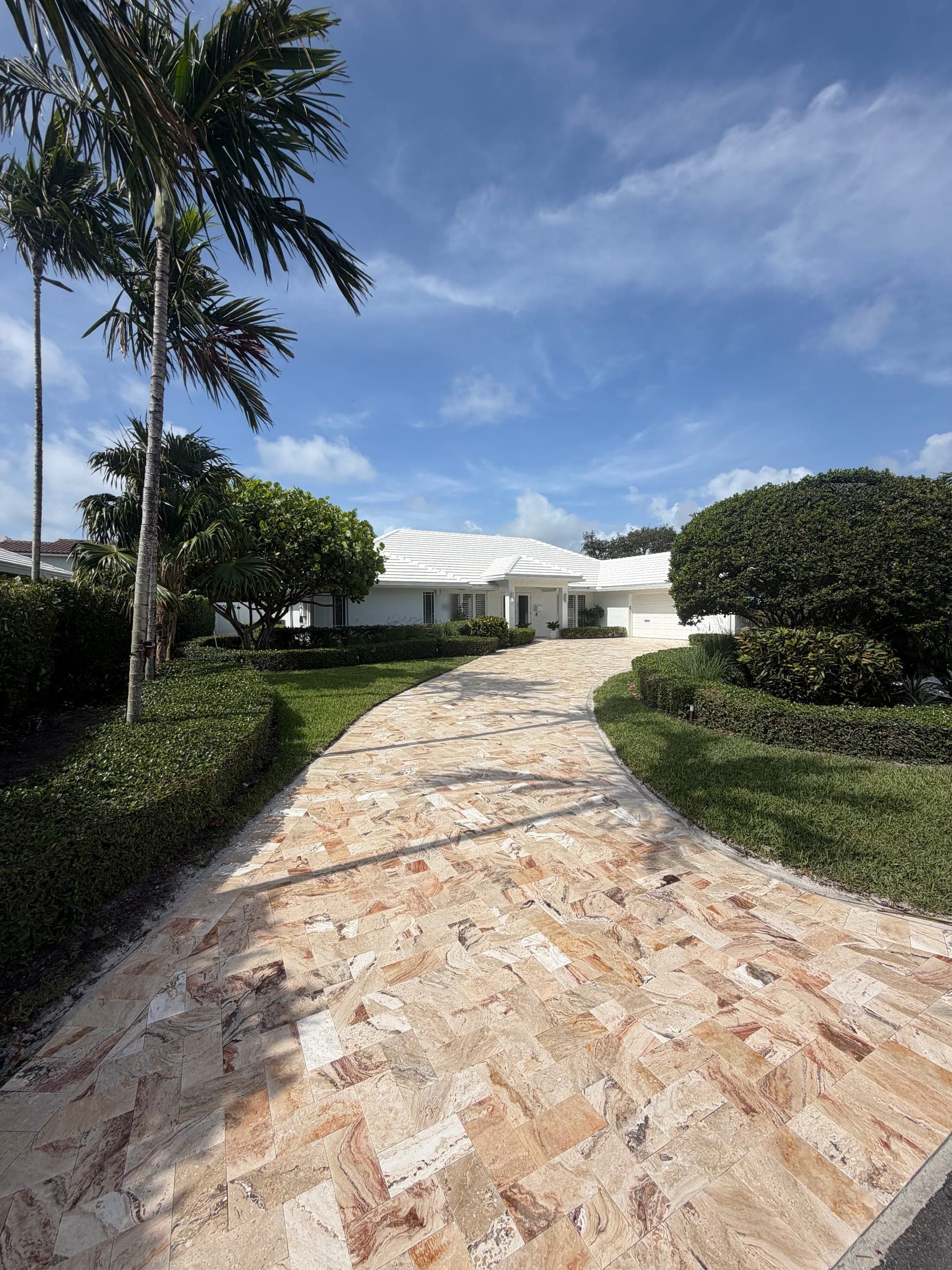 Completed travertine paver driveway with herringbone pattern leading to the home