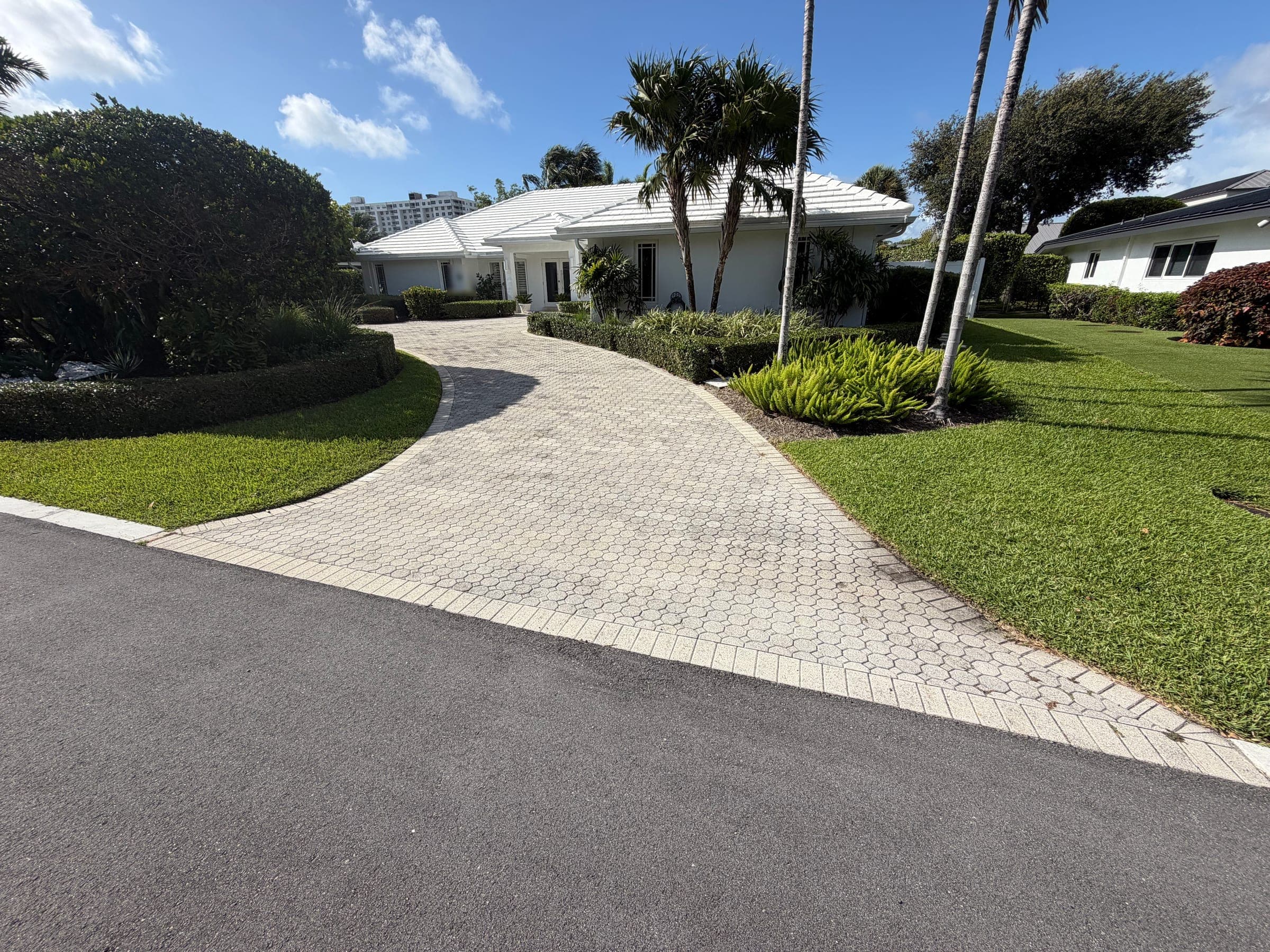 Existing paver driveway before travertine replacement, curving toward the home's entrance