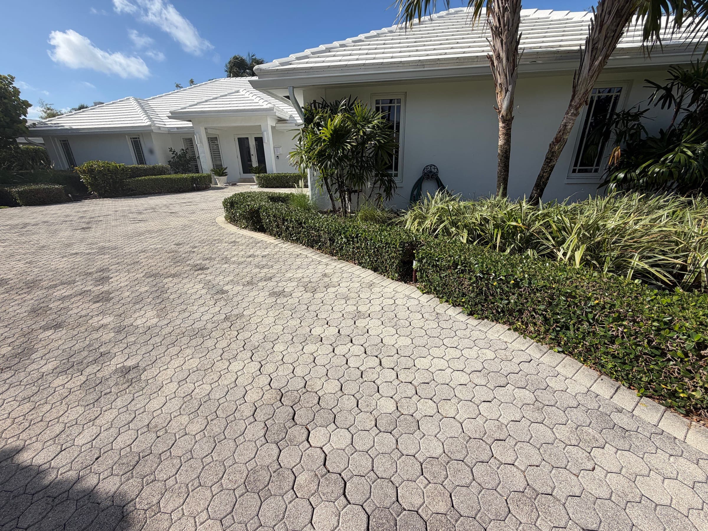 Existing driveway pavers before replacement, viewed from beside the home
