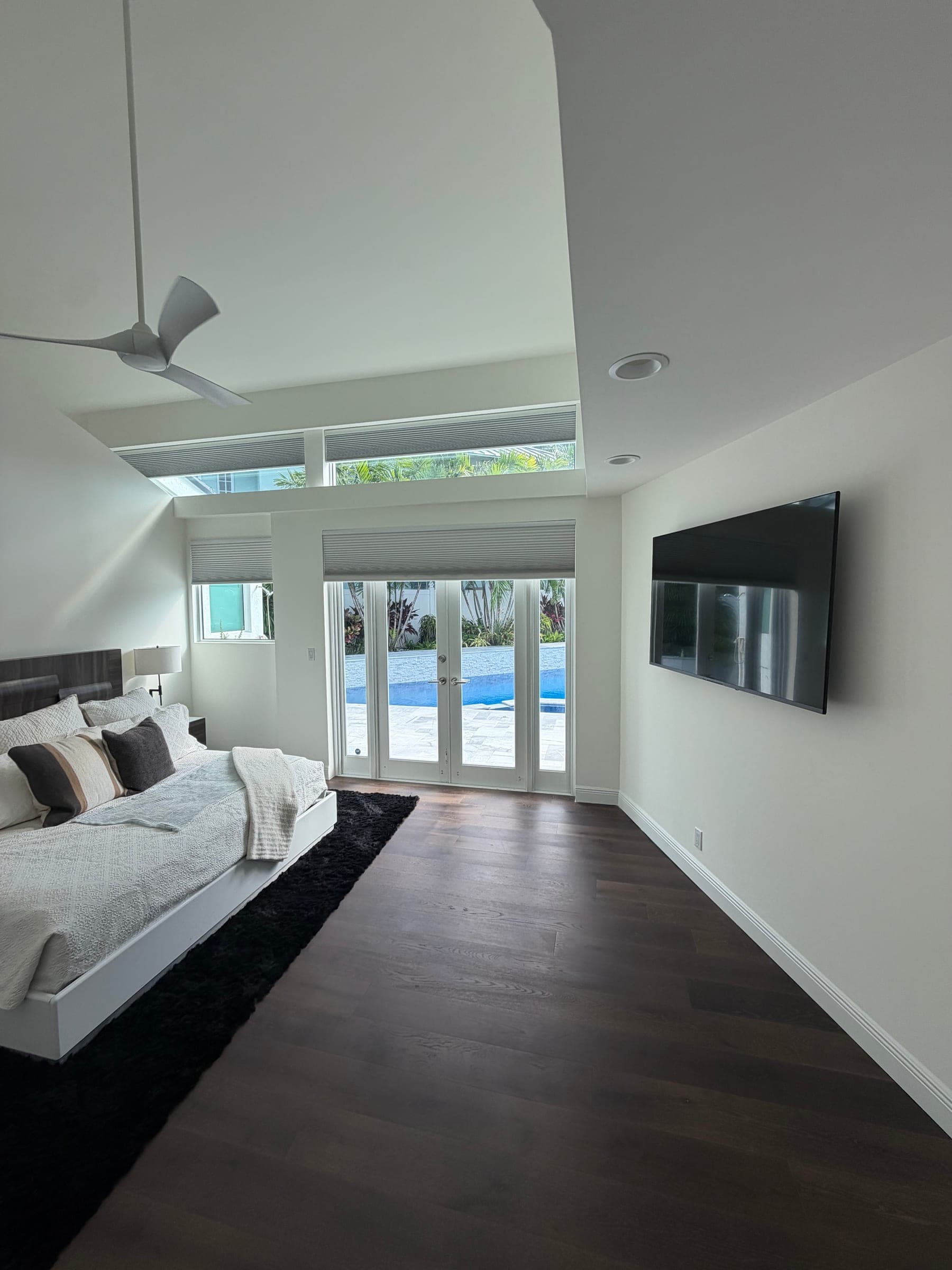 Primary bedroom sitting area with wall-mounted TV and dark wood flooring