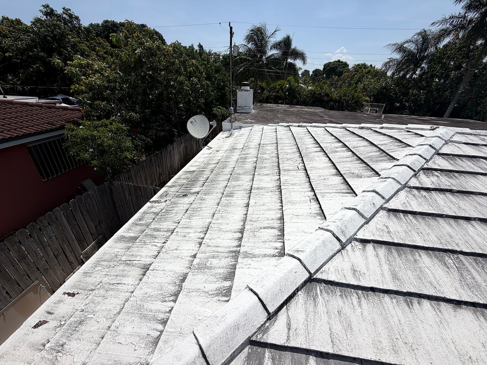 Existing roof surface before the shingle and modified bitumen roof replacement, viewed near the fence line